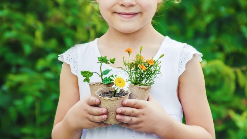 Uma garota segurando pequenos vasos de plantas que ela cultiva